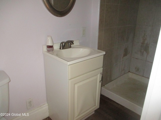 bathroom featuring tiled shower, vanity, toilet, and hardwood / wood-style floors