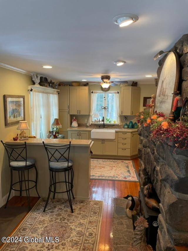 kitchen featuring crown molding, wood-type flooring, sink, and a breakfast bar