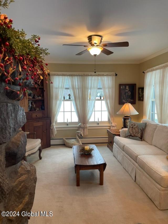 carpeted living room with ornamental molding and ceiling fan