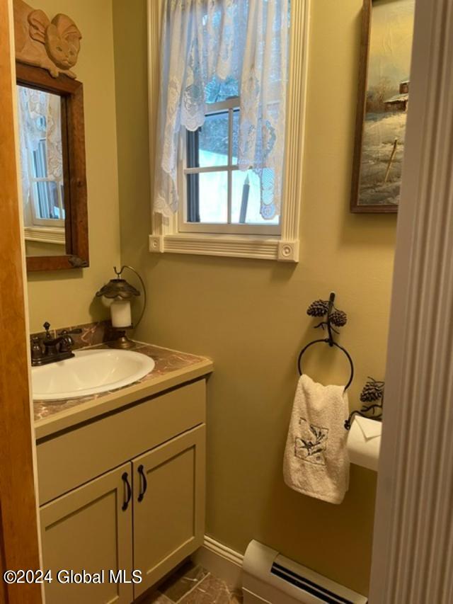 bathroom with toilet, oversized vanity, and baseboard heating