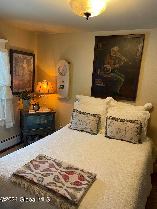 bedroom with dark wood-type flooring, a baseboard heating unit, and a wood stove