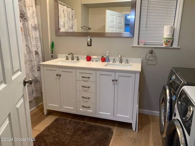 bathroom with washing machine and clothes dryer, oversized vanity, hardwood / wood-style floors, and double sink