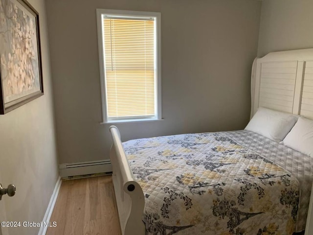 bedroom with light hardwood / wood-style floors and a baseboard radiator