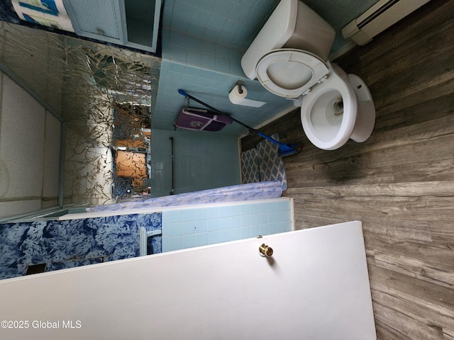 bathroom featuring baseboard heating, wood walls, and toilet