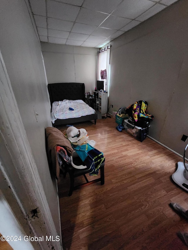 bedroom with wood-type flooring and a drop ceiling