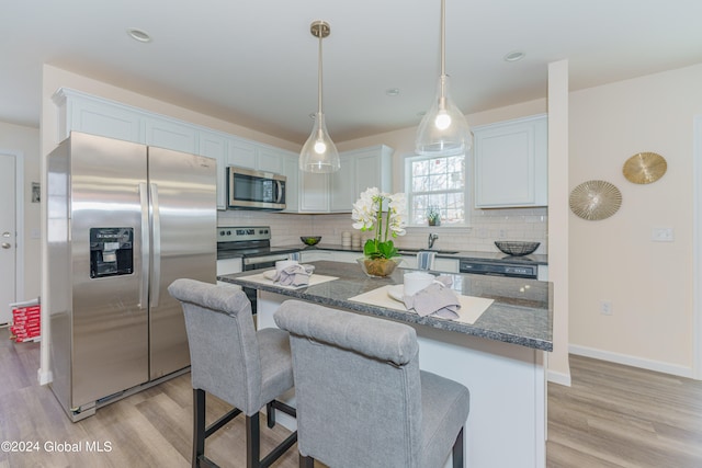 kitchen featuring tasteful backsplash, appliances with stainless steel finishes, white cabinetry, and light wood-type flooring