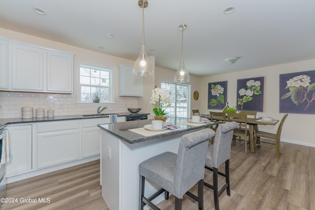 kitchen featuring backsplash, light hardwood / wood-style floors, decorative light fixtures, and white cabinetry