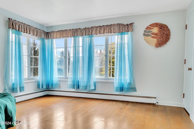 interior space with a healthy amount of sunlight, hardwood / wood-style flooring, and baseboard heating