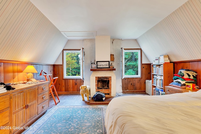 bedroom featuring wooden walls, vaulted ceiling, and a brick fireplace