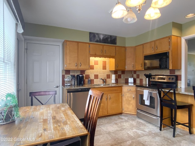 kitchen with hanging light fixtures, sink, tasteful backsplash, stainless steel appliances, and a notable chandelier