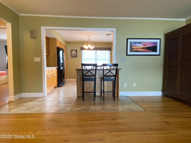 unfurnished dining area with light wood-type flooring, a chandelier, and ornamental molding