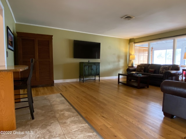 living room with light wood-type flooring and ornamental molding