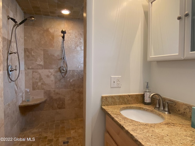 bathroom with tiled shower and vanity