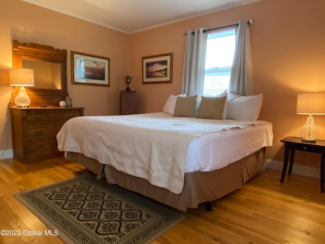 bedroom with light hardwood / wood-style floors and crown molding