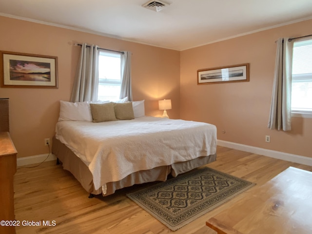 bedroom with light hardwood / wood-style flooring, multiple windows, and crown molding