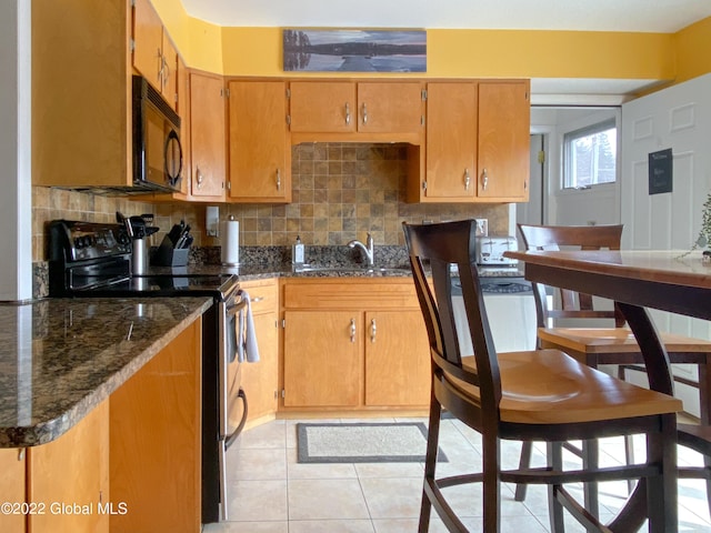 kitchen with decorative backsplash, stainless steel electric range, light tile patterned floors, dark stone counters, and sink