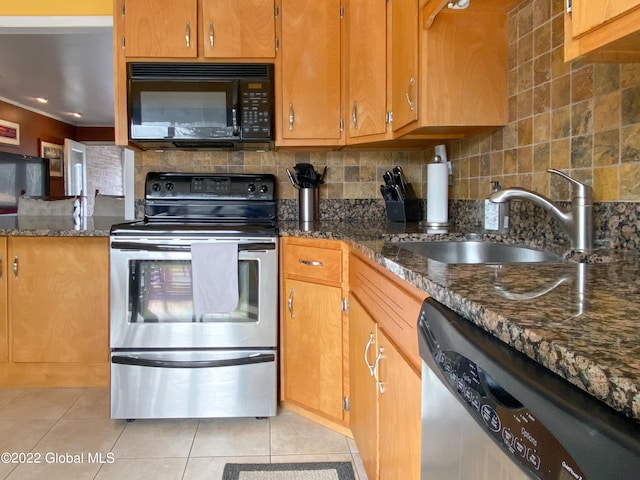 kitchen with dark stone countertops, backsplash, light tile patterned floors, stainless steel appliances, and sink