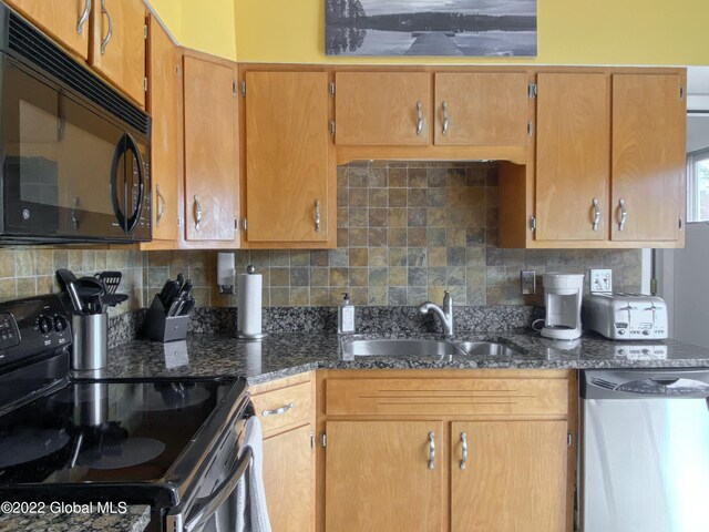 kitchen featuring decorative backsplash, dark stone countertops, sink, and stainless steel appliances