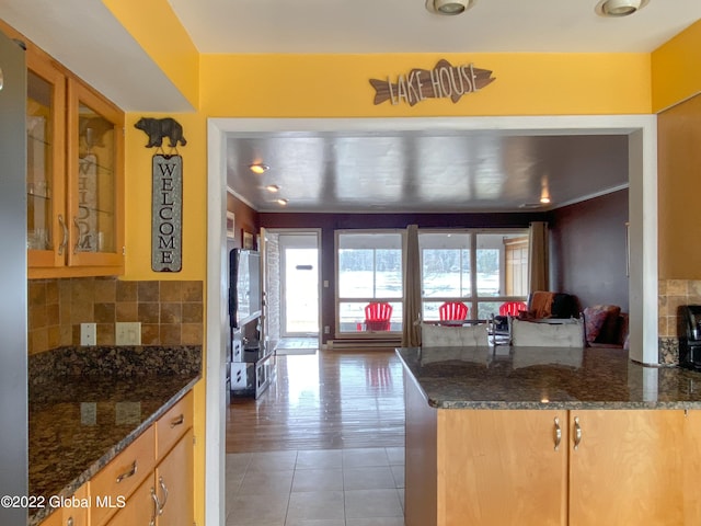 kitchen with dark stone counters, decorative backsplash, kitchen peninsula, and hardwood / wood-style floors