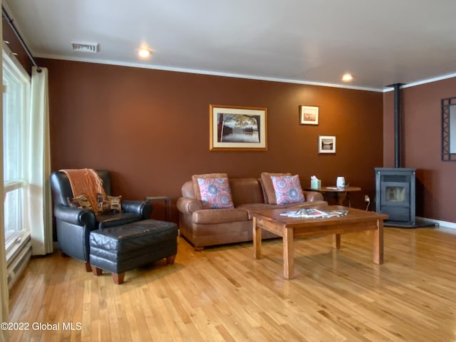 living room featuring a wood stove, light hardwood / wood-style floors, and crown molding