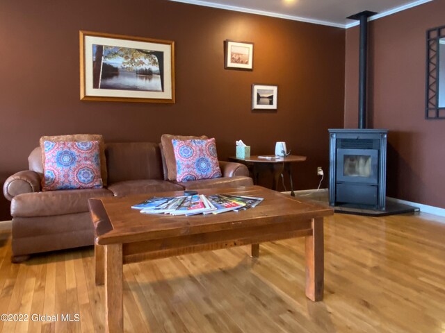 sitting room with light wood-type flooring, ornamental molding, and a wood stove