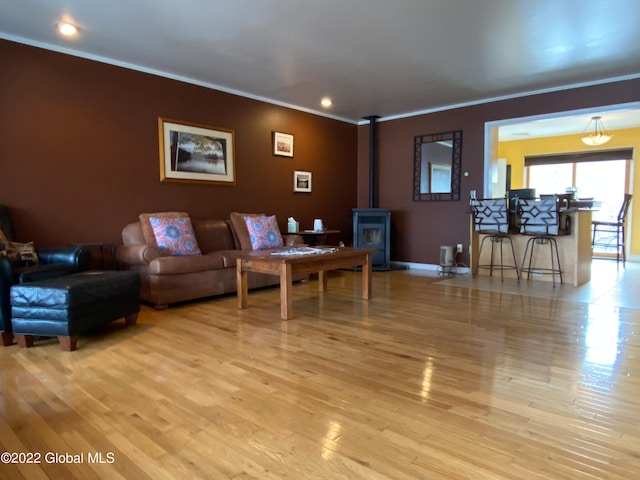 living room with light wood-type flooring, crown molding, and a wood stove