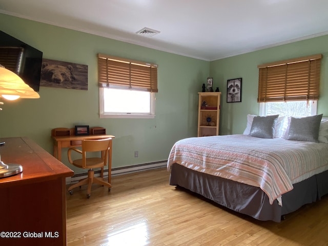 bedroom featuring ornamental molding, light wood-type flooring, and a baseboard heating unit