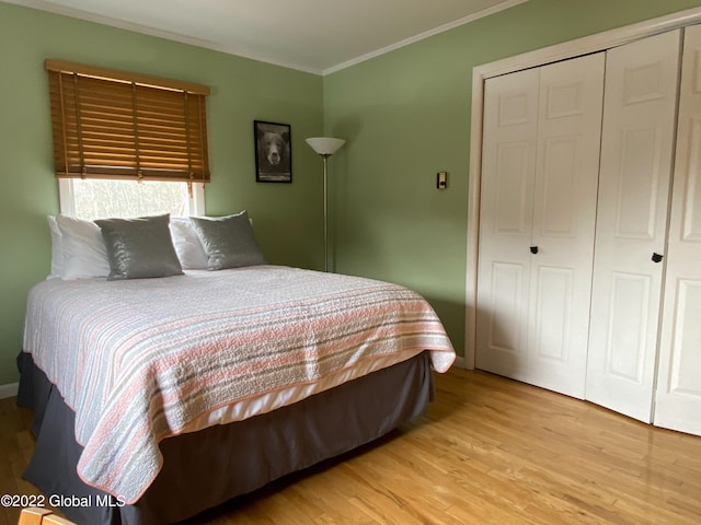 bedroom featuring crown molding, light hardwood / wood-style flooring, and a closet