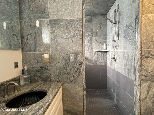 bathroom with tiled shower and vanity