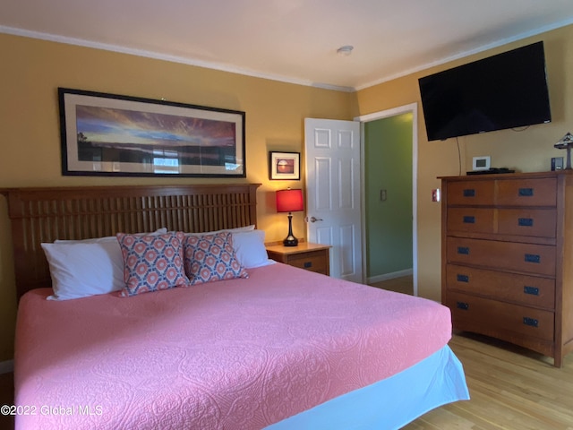 bedroom featuring ornamental molding and light hardwood / wood-style floors