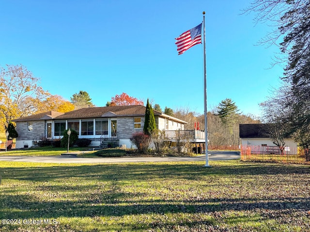 view of front of house featuring a deck, a front lawn, and a sunroom