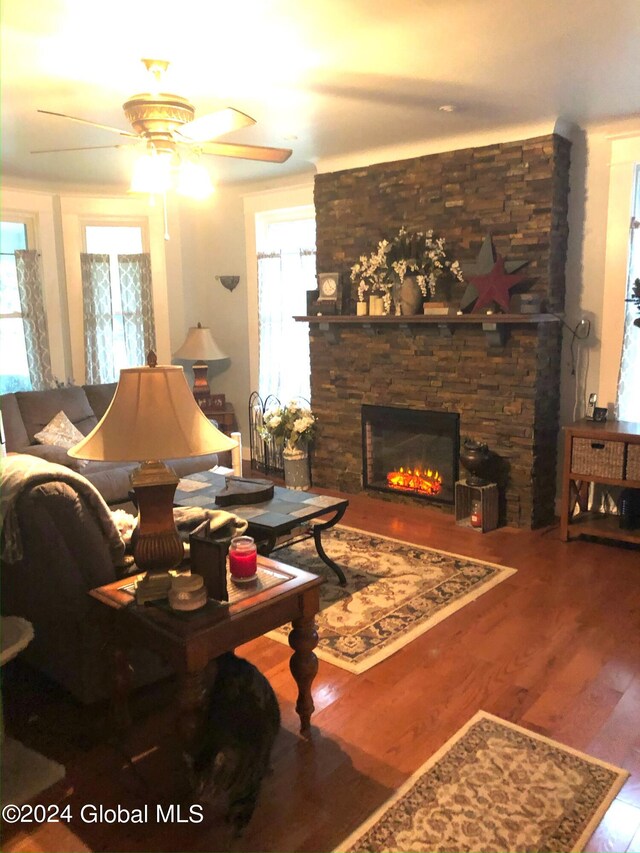living room featuring ceiling fan, a stone fireplace, hardwood / wood-style floors, and a healthy amount of sunlight