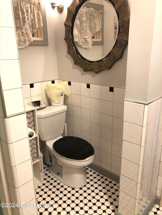 bathroom featuring tile walls, tile floors, and toilet