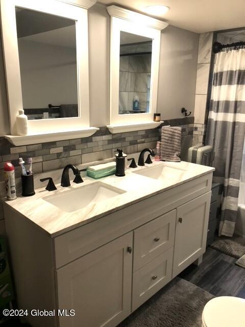 bathroom featuring backsplash, double sink vanity, toilet, and hardwood / wood-style flooring