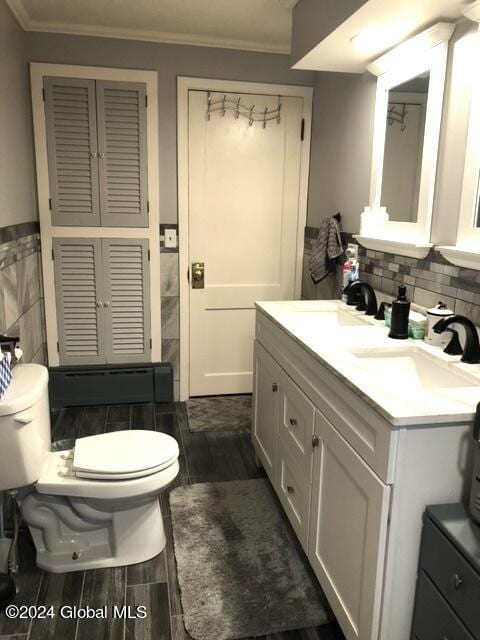 bathroom with crown molding, backsplash, toilet, and vanity with extensive cabinet space