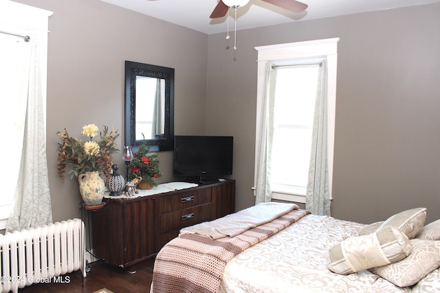 bedroom with dark hardwood / wood-style floors, ceiling fan, and radiator