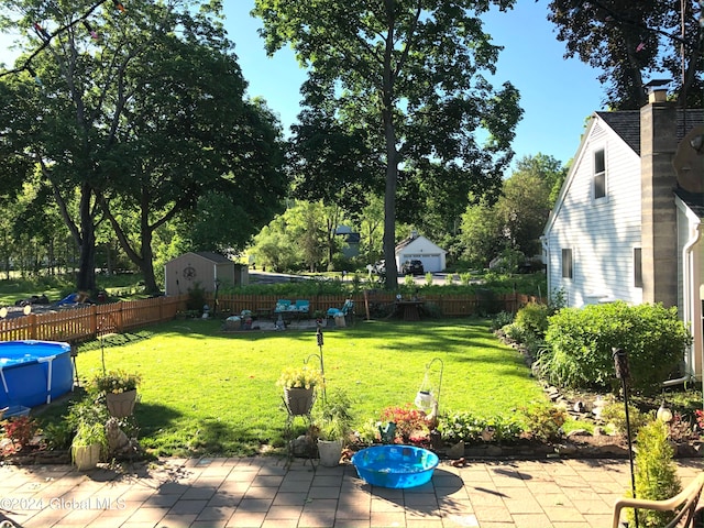 view of yard featuring a fenced in pool, a storage shed, and a patio