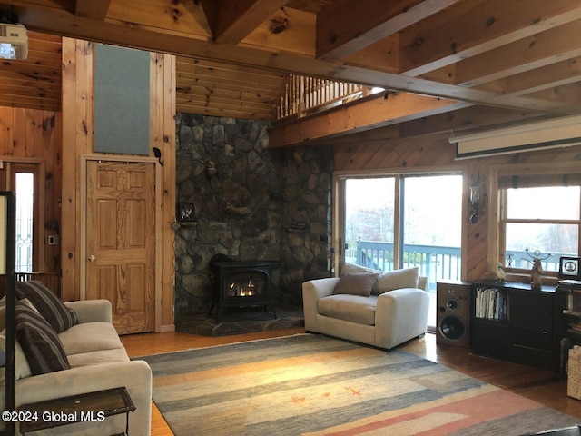 living room with dark hardwood / wood-style flooring, a wood stove, beam ceiling, and wooden walls