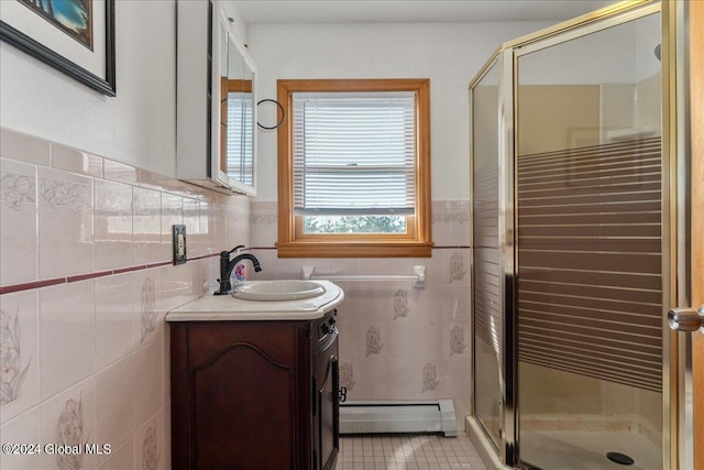 bathroom with tile flooring, baseboard heating, tile walls, a shower with door, and vanity