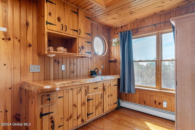 kitchen with wood walls, a baseboard radiator, a wealth of natural light, and light hardwood / wood-style flooring