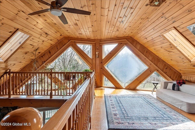 interior space with vaulted ceiling with skylight, light wood-type flooring, and a healthy amount of sunlight