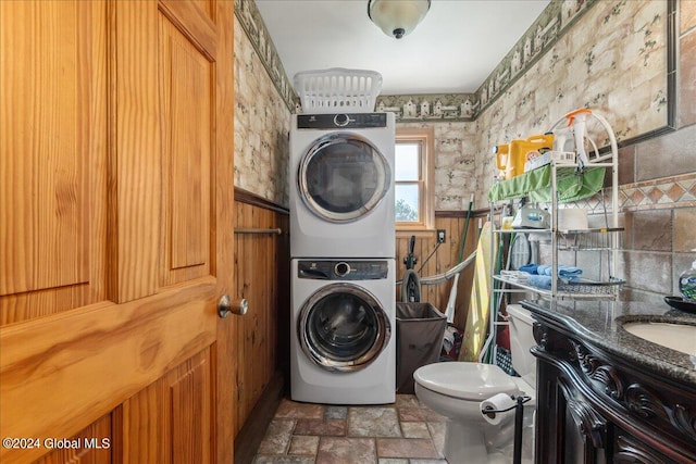 laundry area featuring dark tile floors and stacked washer / drying machine