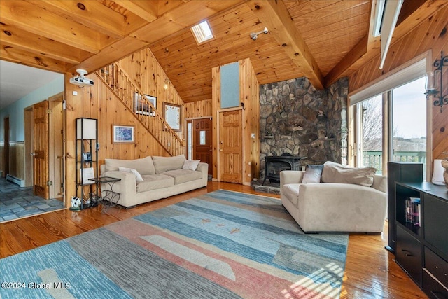 unfurnished living room featuring hardwood / wood-style floors, beamed ceiling, wooden ceiling, wooden walls, and a stone fireplace