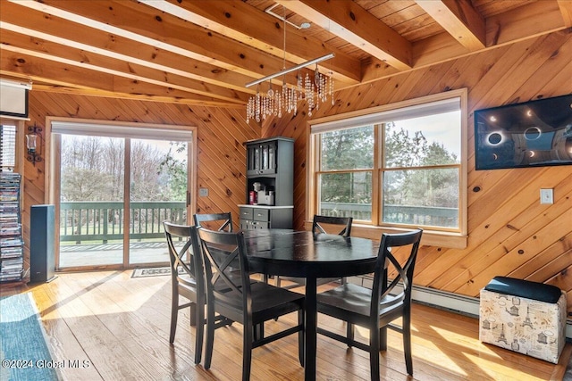 dining area with wood walls, light hardwood / wood-style flooring, a chandelier, and plenty of natural light