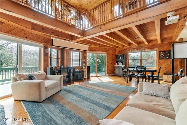 living room with beam ceiling, light hardwood / wood-style floors, wood ceiling, and wood walls