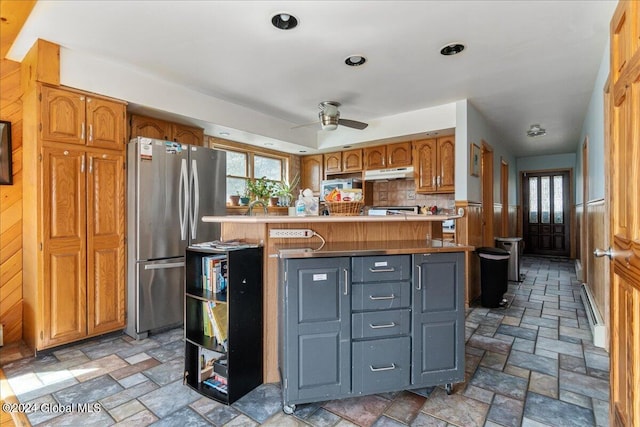 kitchen with kitchen peninsula, stainless steel fridge, ceiling fan, light tile flooring, and tasteful backsplash