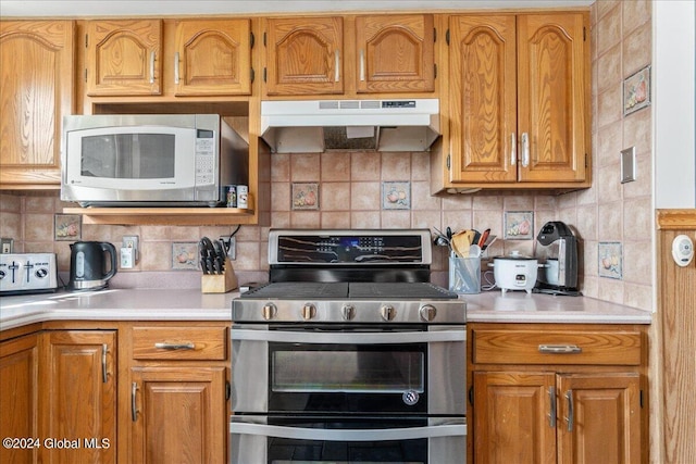 kitchen featuring stainless steel range oven, tasteful backsplash, and wall chimney exhaust hood