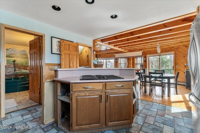 kitchen featuring pendant lighting, hardwood / wood-style floors, stainless steel fridge, and wood walls