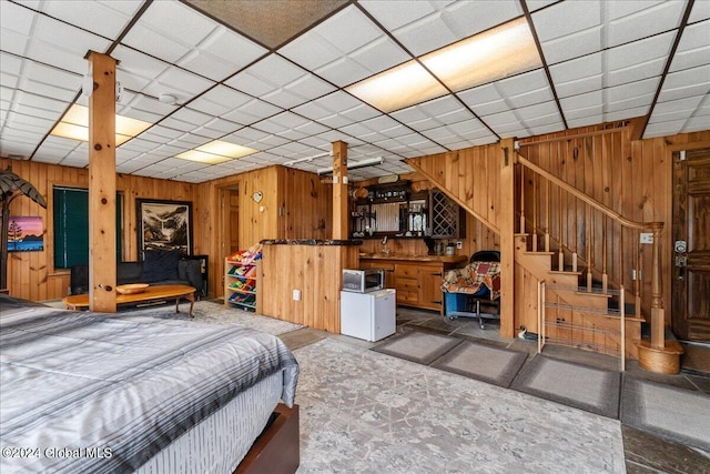 tiled bedroom with bar, wood walls, and a paneled ceiling