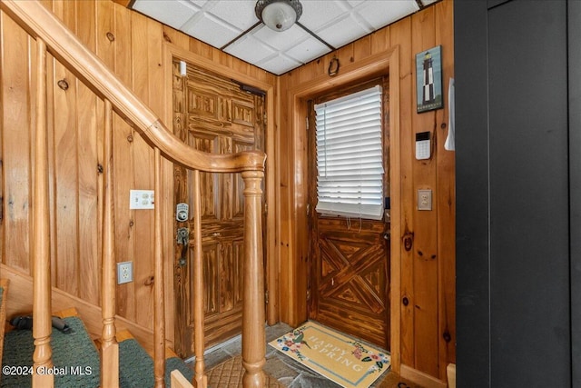 interior space featuring a paneled ceiling and wooden walls